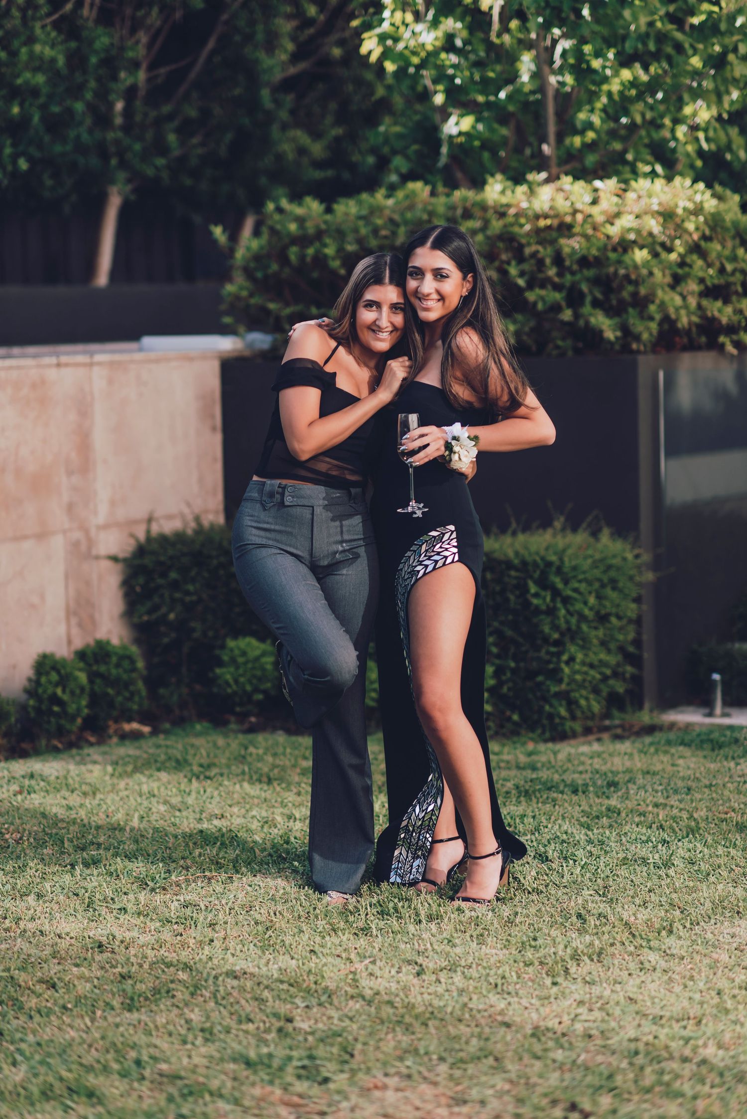 Two people embracing on grass during an outdoor photoshoot as they share a joyful moment together.