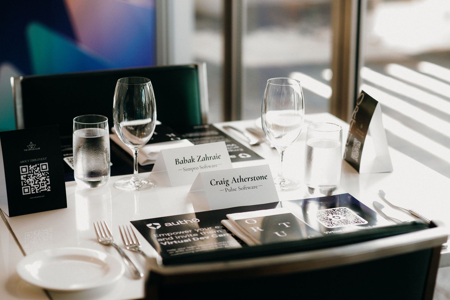 Close-up view of formal place settings with wine glasses and black menu cards on a white tablecloth.