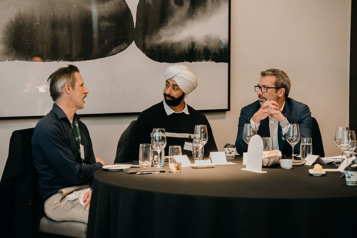 Business professionals engaged in discussion at a conference table with water glasses and documents.
