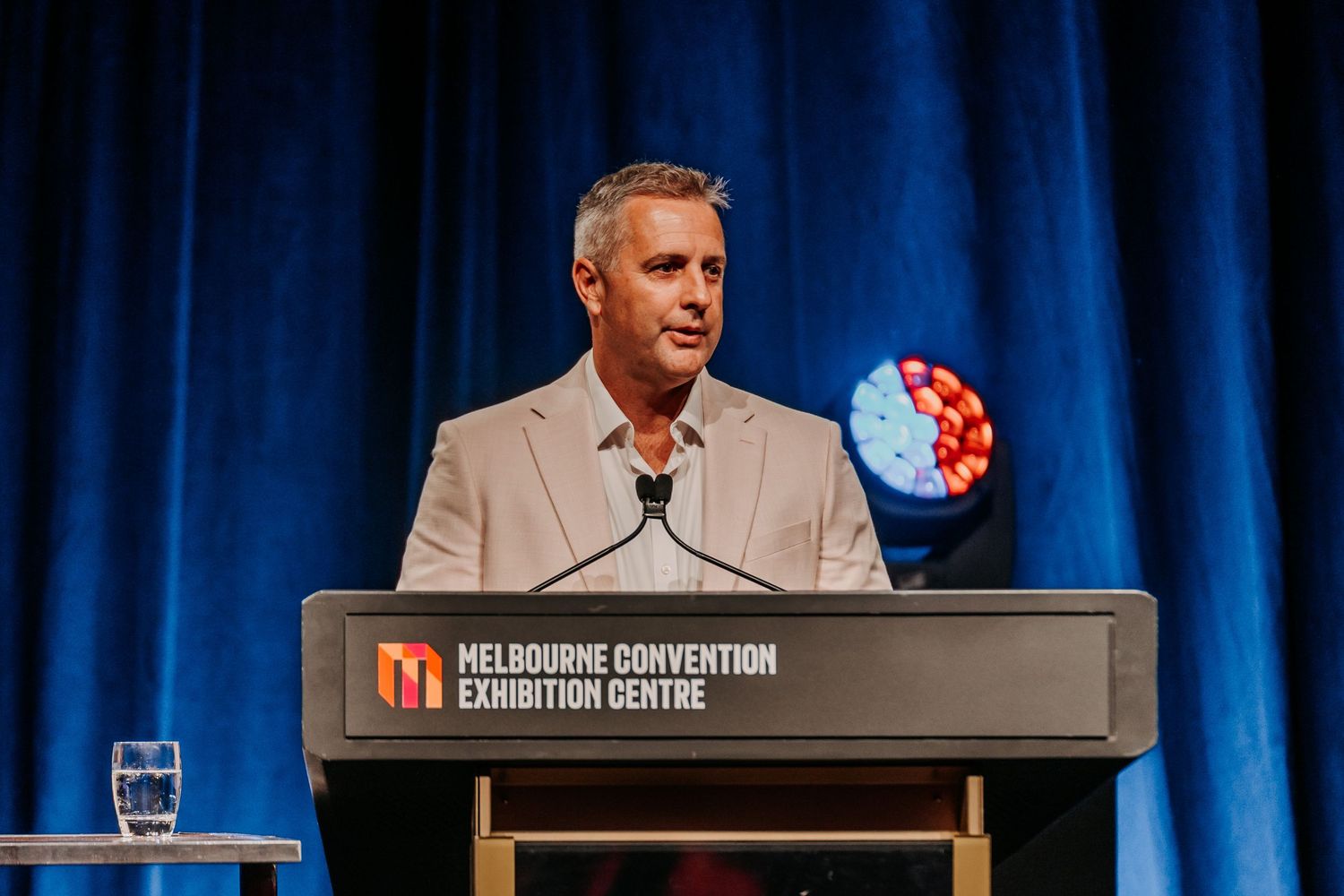 Speaker presenting at podium during business conference at Melbourne Convention Exhibition Centre.