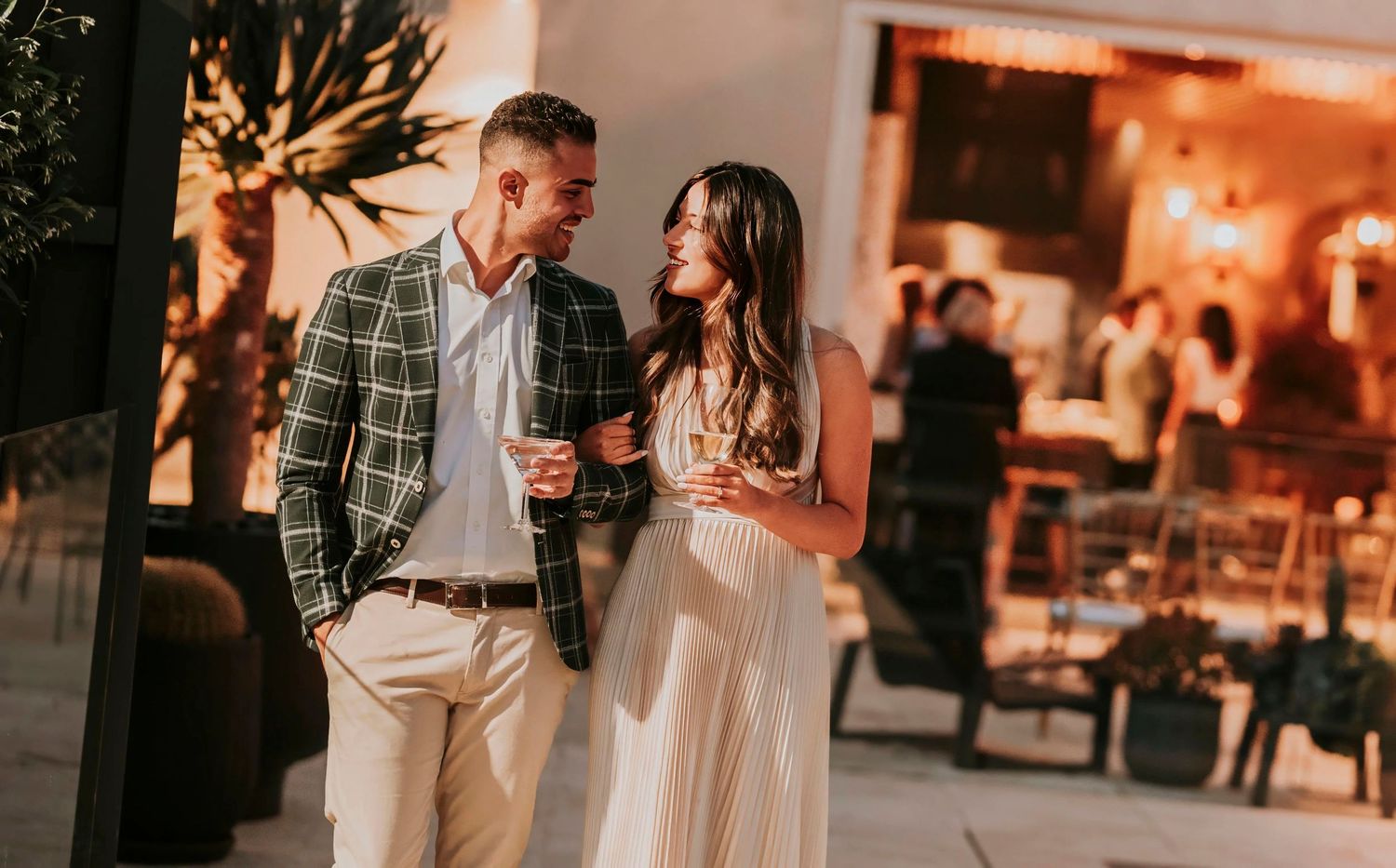 A romantic couple enjoys wine together in a warmly lit restaurant setting during an intimate evening out.