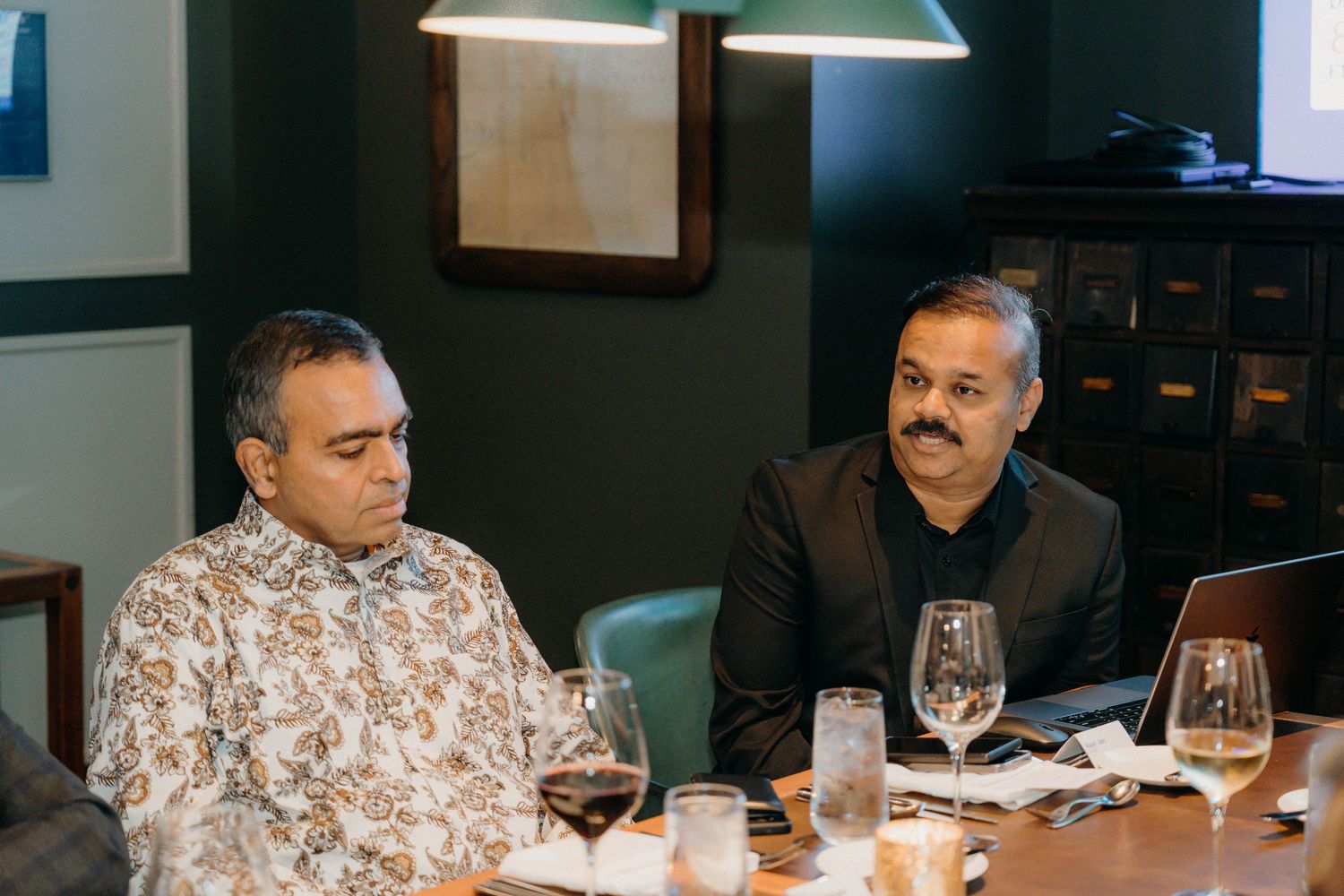 People seated at a restaurant table review menus and wine glasses while having a business dinner meeting.