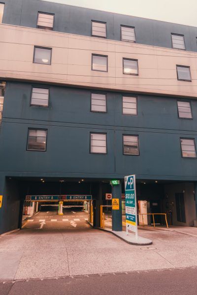 A panoramic view of a modern parking garage entrance with multiple bays and directional signage.