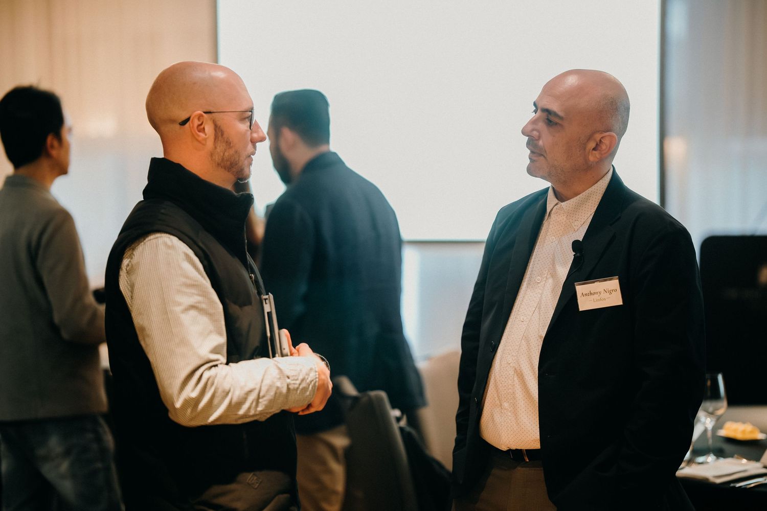 Business professionals engage in conversation during a networking event in a bright office setting.