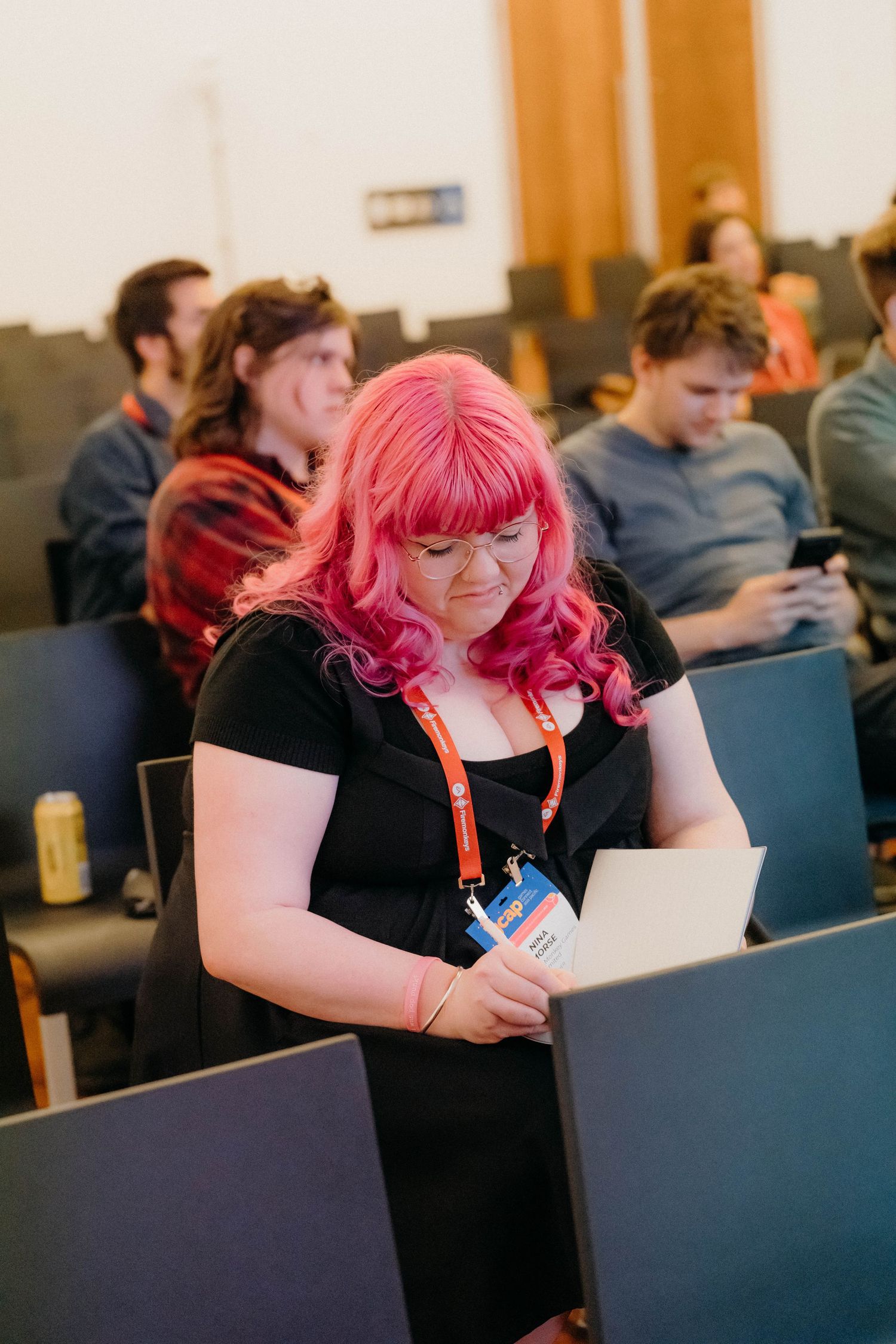A person with bright pink hair wearing black attends a conference, shown in a series of photos at different angles.