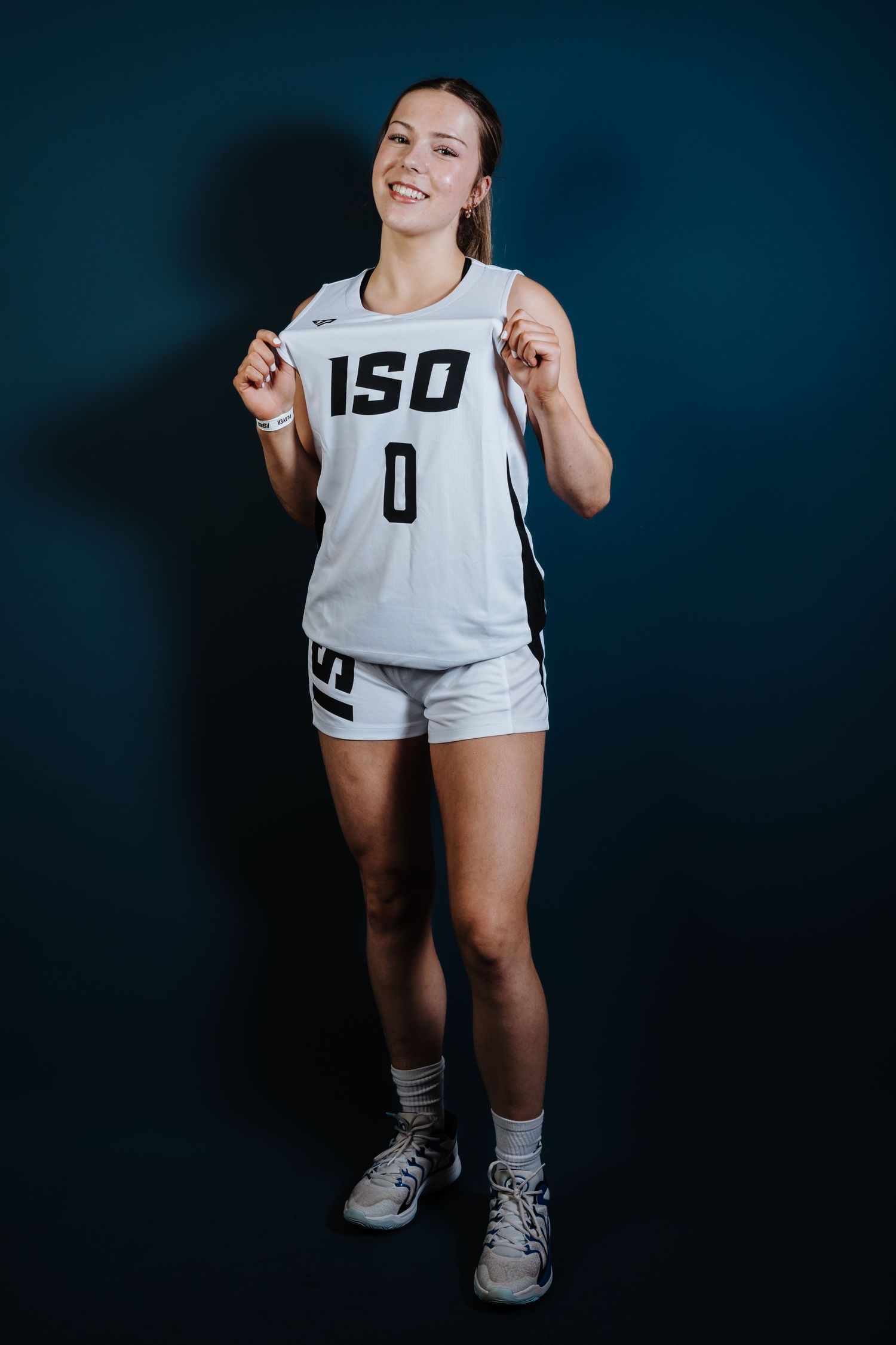 Athletic figure in white jersey and shorts poses against dark background in dynamic sports photography series.