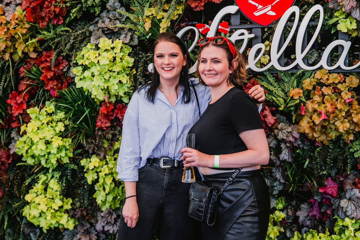 A couple poses together outdoors against a vibrant backdrop of red and green autumn foliage.