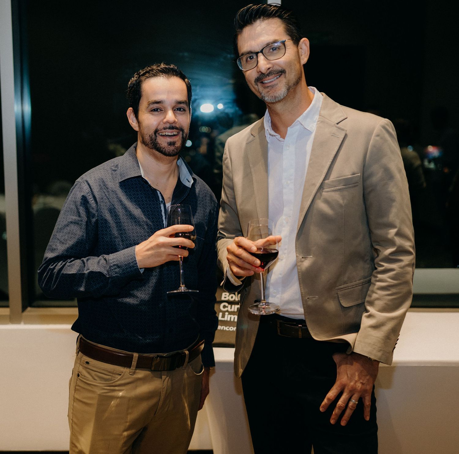 Two colleagues enjoying drinks at an evening networking event in business casual attire.