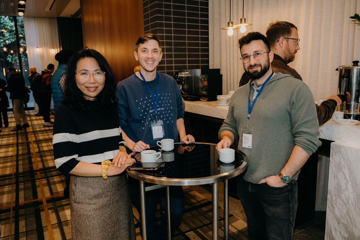 A group of colleagues gather around a small table at a networking event in a modern venue with ambient lighting.