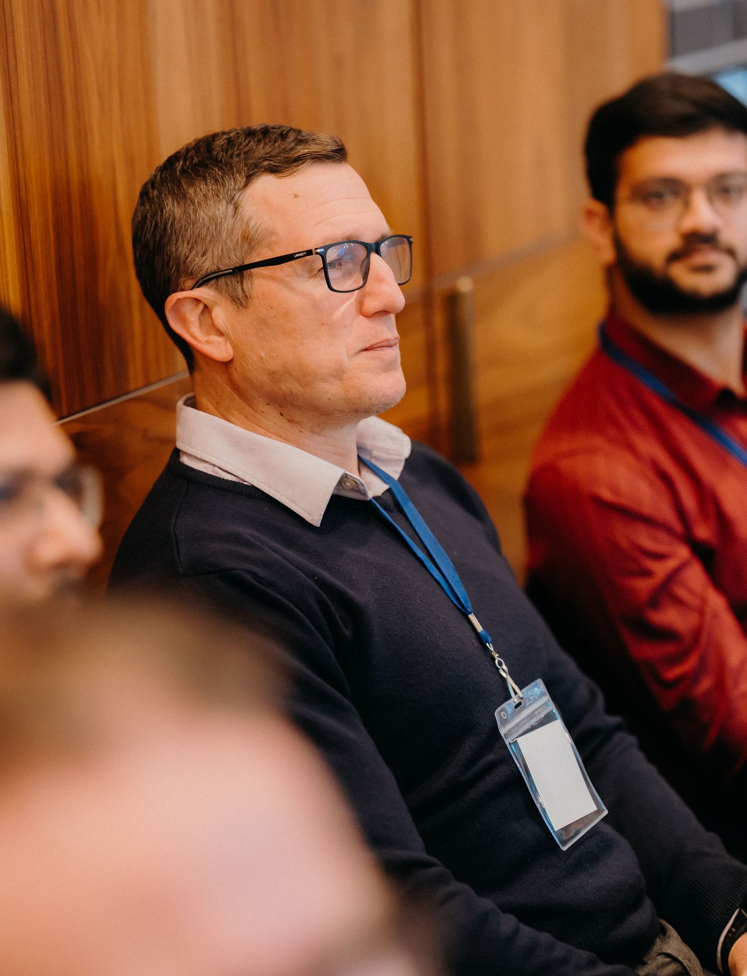Conference attendees seated in a row listen attentively during a professional business presentation.