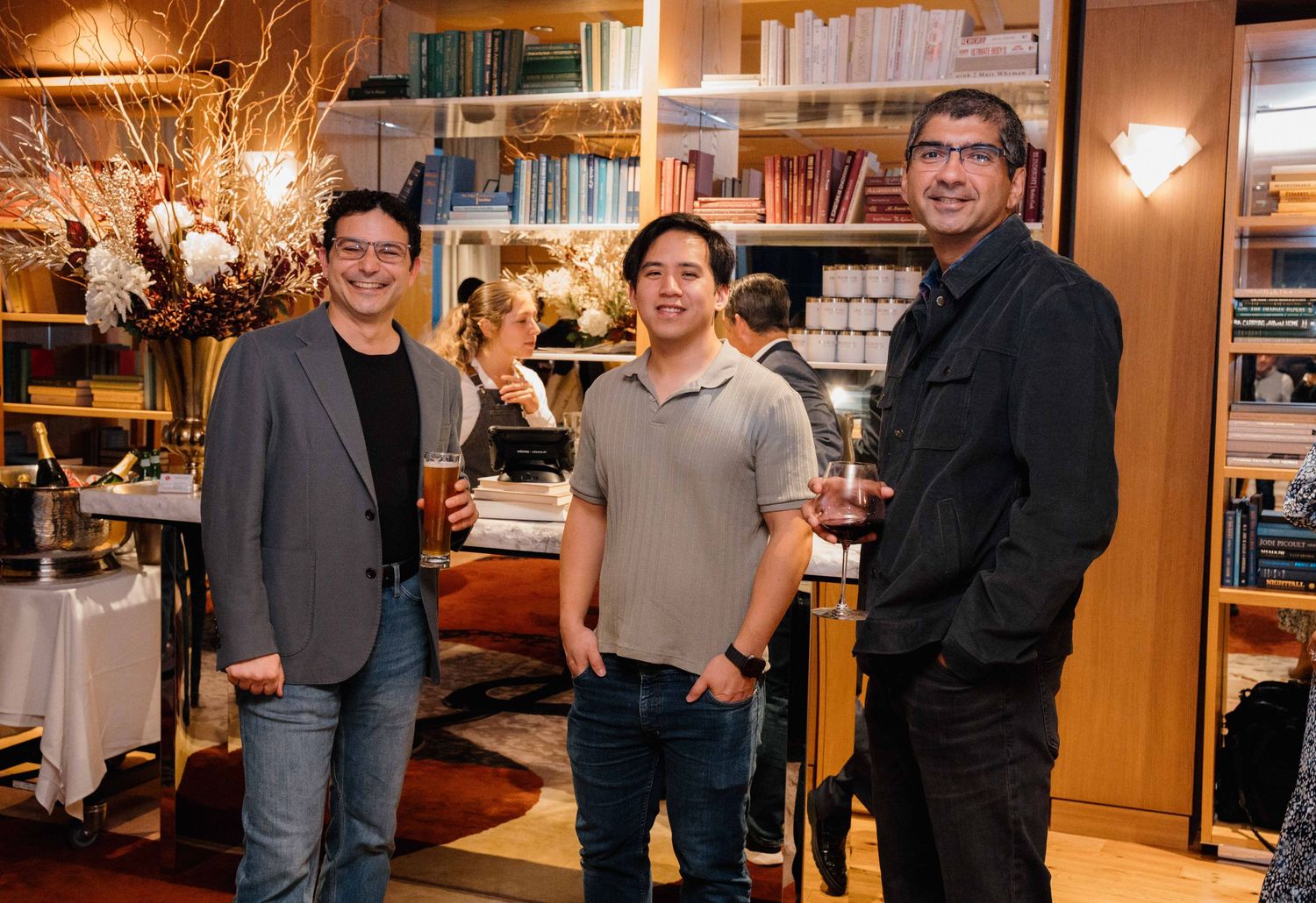 People gathered in a cozy home library setting with warm lighting and bookshelves in the background.
