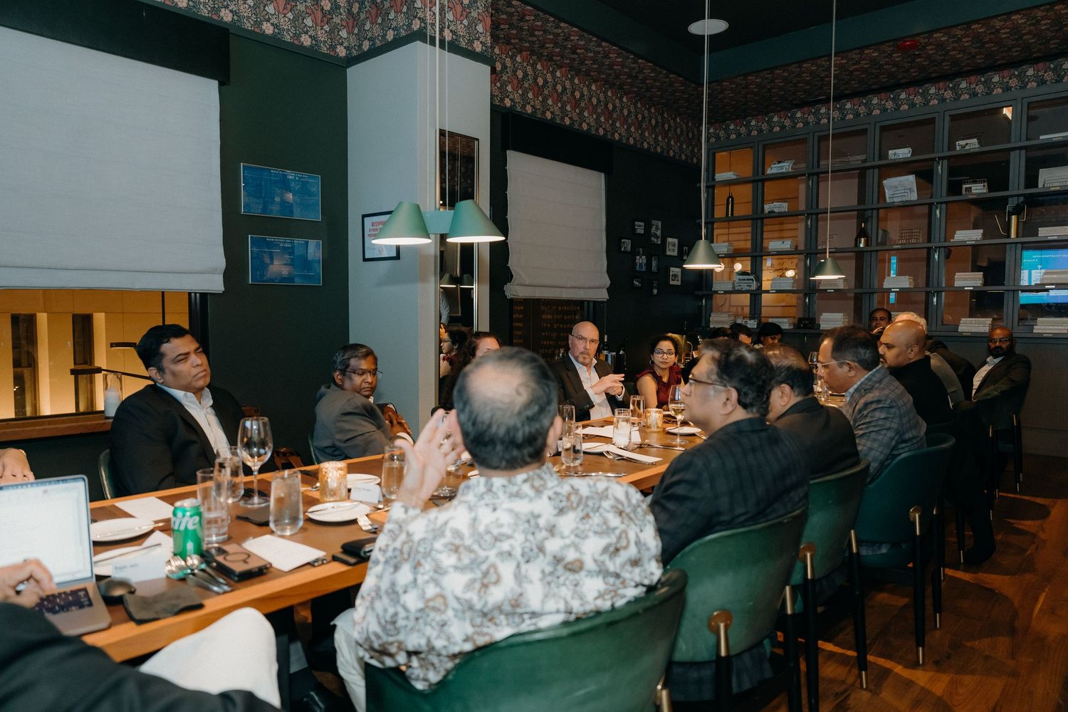 Business professionals gather around conference tables in a modern office space for a collaborative meeting.