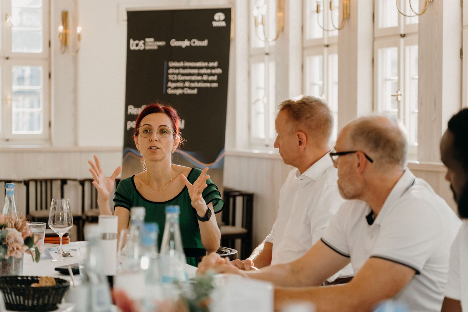 Woman presenting at Google Cloud business roundtable discussion with attentive male colleagues in bright conference room.