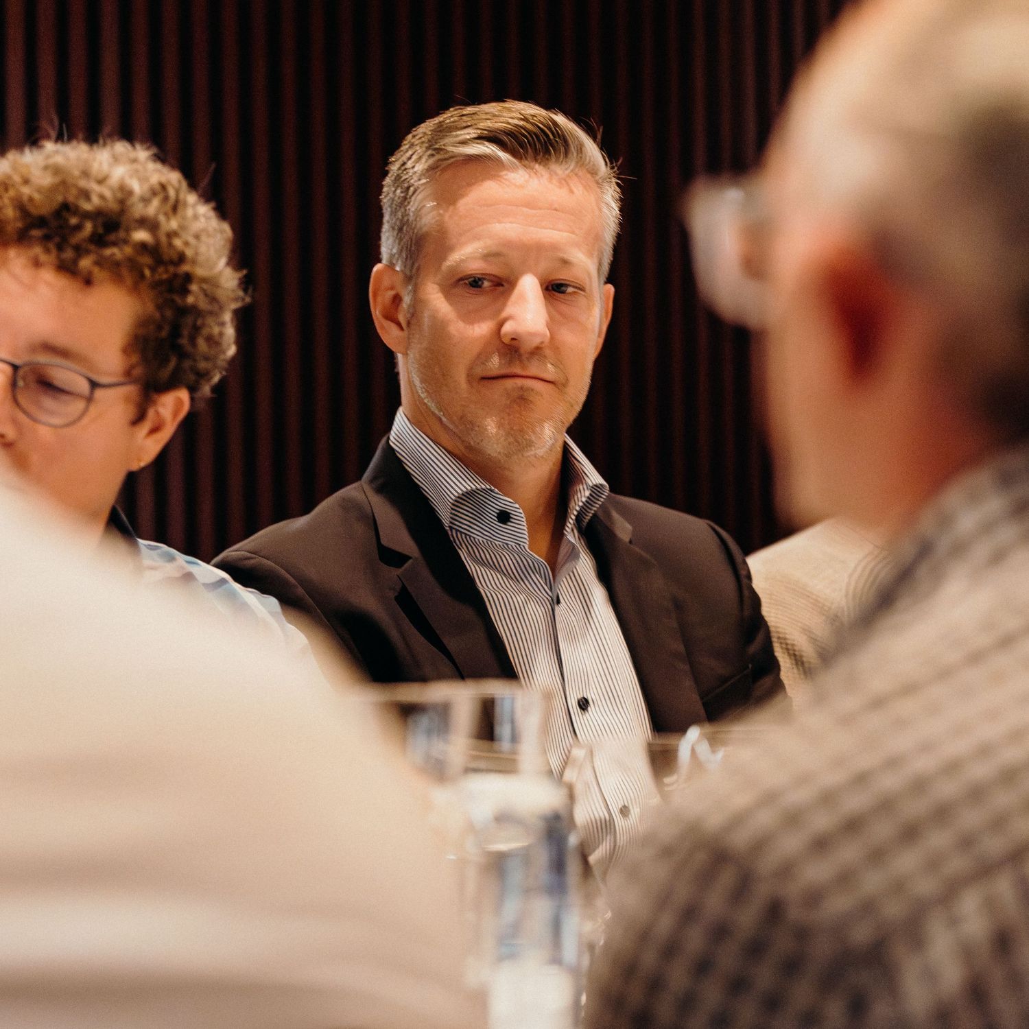 Business professionals engaged in conversation around a conference table during a meeting.