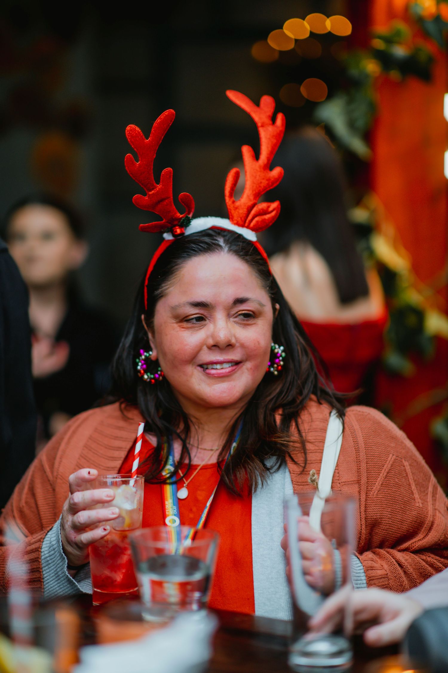 A sequence of festive holiday party photos showing someone wearing reindeer antlers while enjoying drinks at a table.