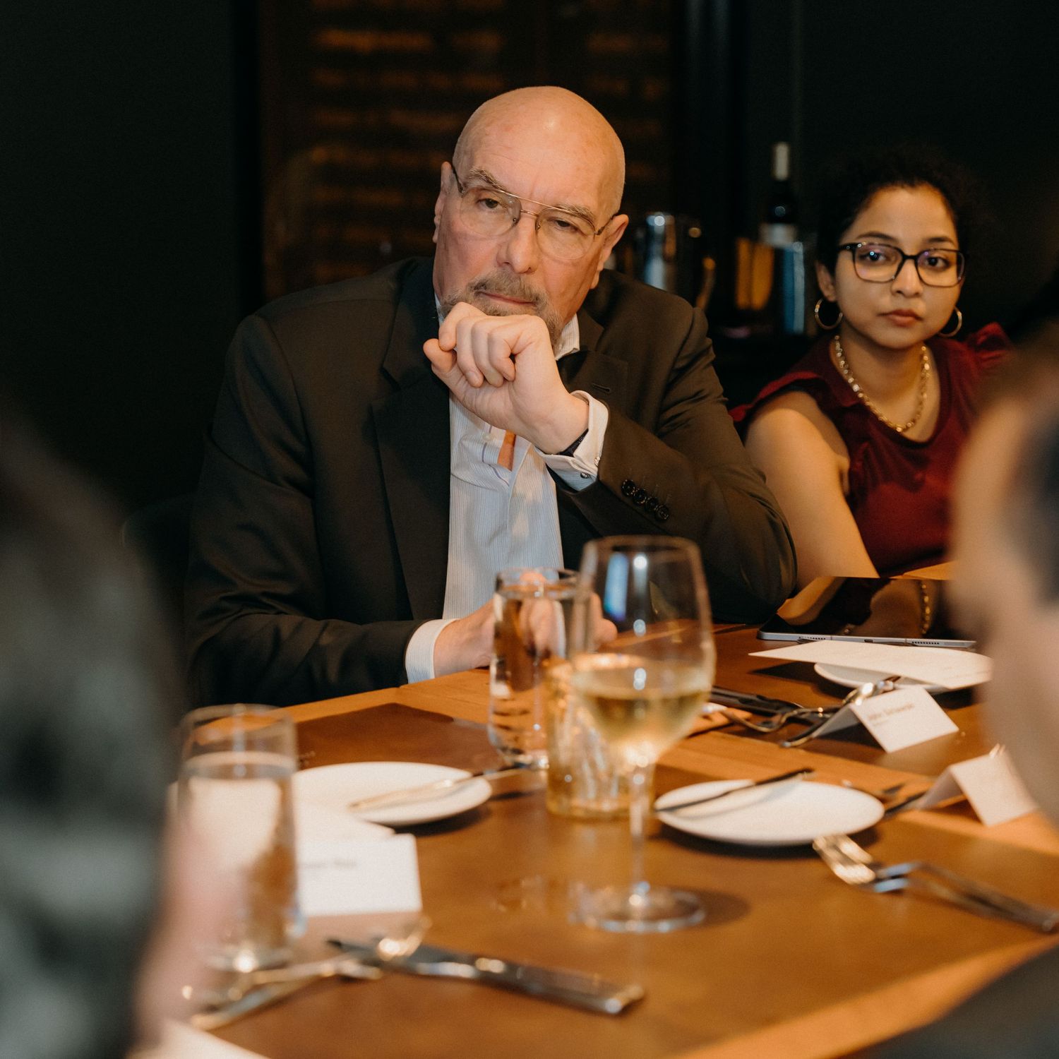 People seated at a wooden table in a restaurant having a business meeting or dinner conversation.