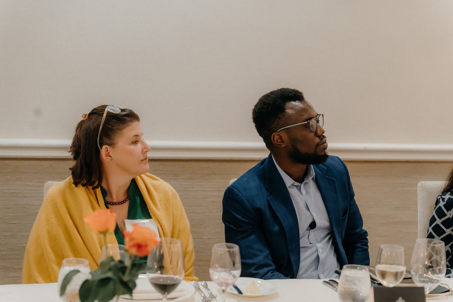 People sitting at a long table during a business meeting in a bright conference room.