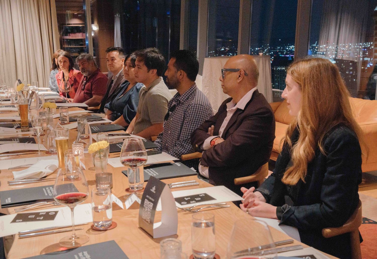 People gathered around a long dining table in an upscale restaurant for a business dinner meeting.