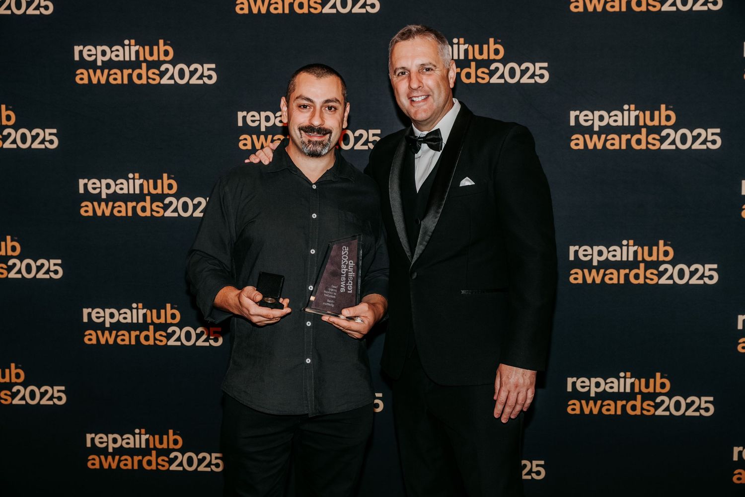 People in formal attire pose for photos at the Repairub Awards 2025 event against a branded step-and-repeat backdrop.