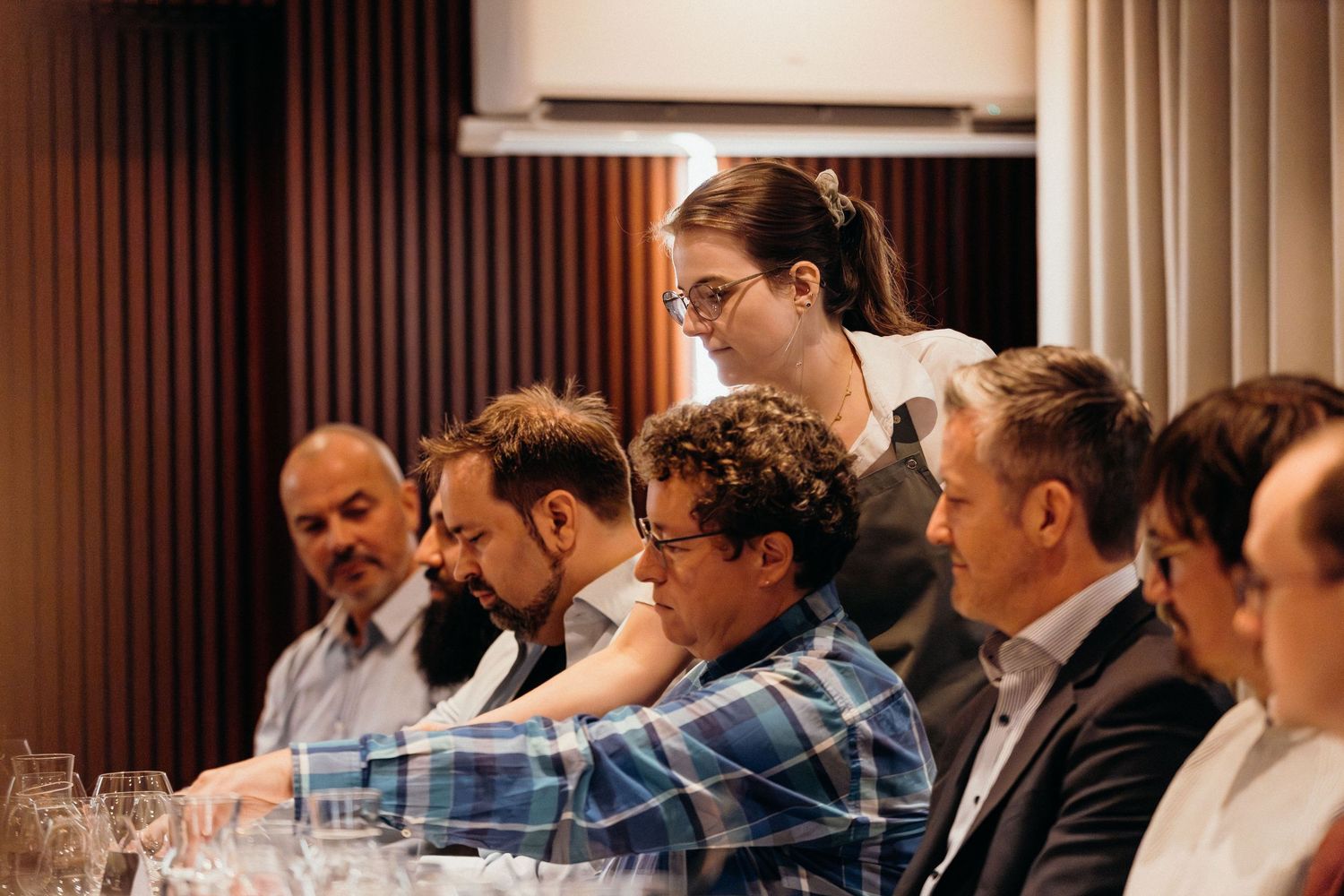 Business professionals seated at long conference tables during a corporate meeting or training session.