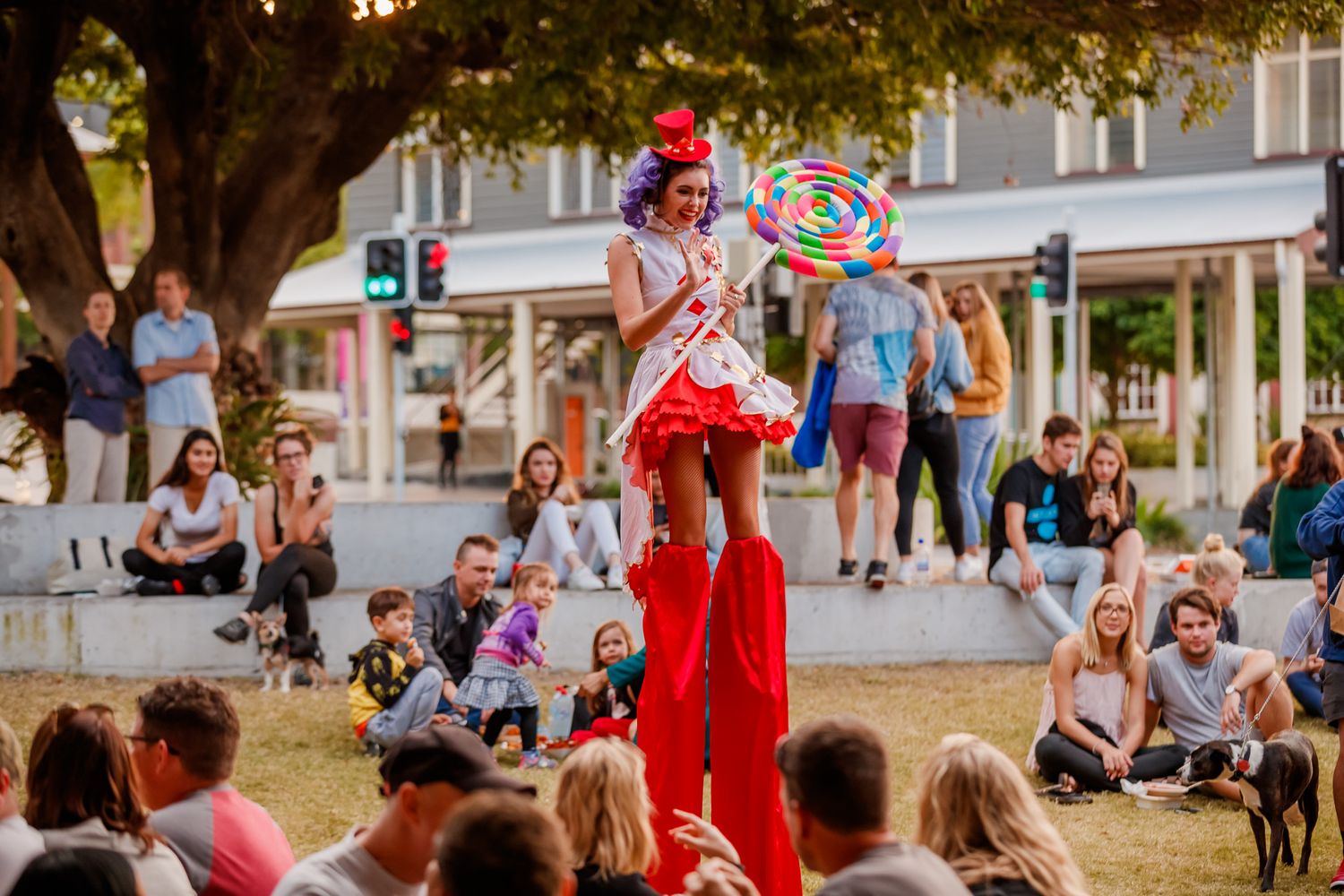 People enjoying entertainment and bubbles at a summer street festival with vendors and crowds along a sidewalk.