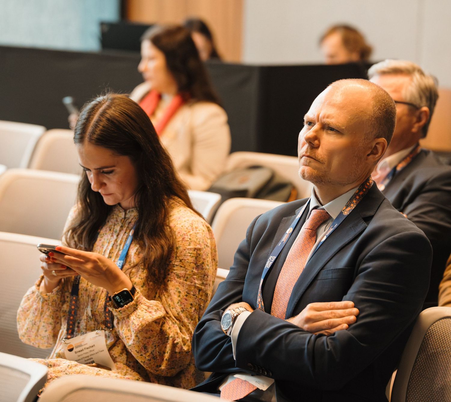 Business professionals sitting in a row during a conference or seminar presentation.