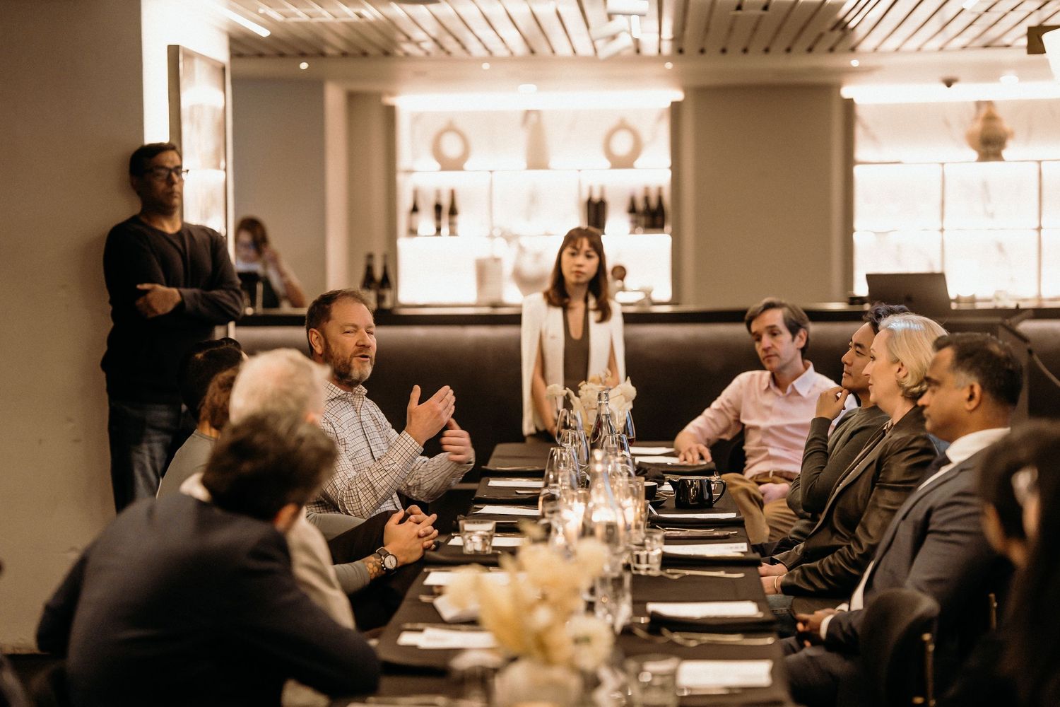 People gathered at a restaurant table engage in conversation during a social dining event.