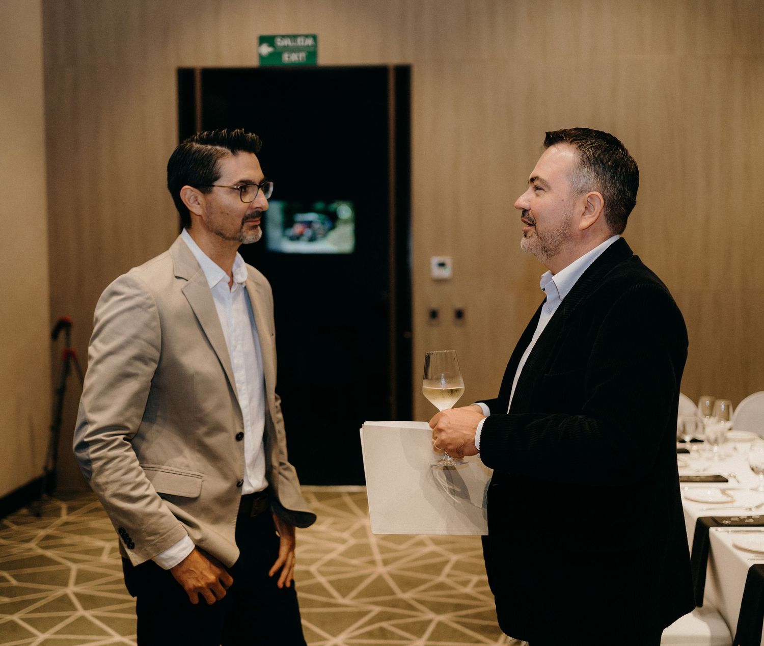Guests in formal attire mingle and socialize at an elegant indoor business reception or networking event.