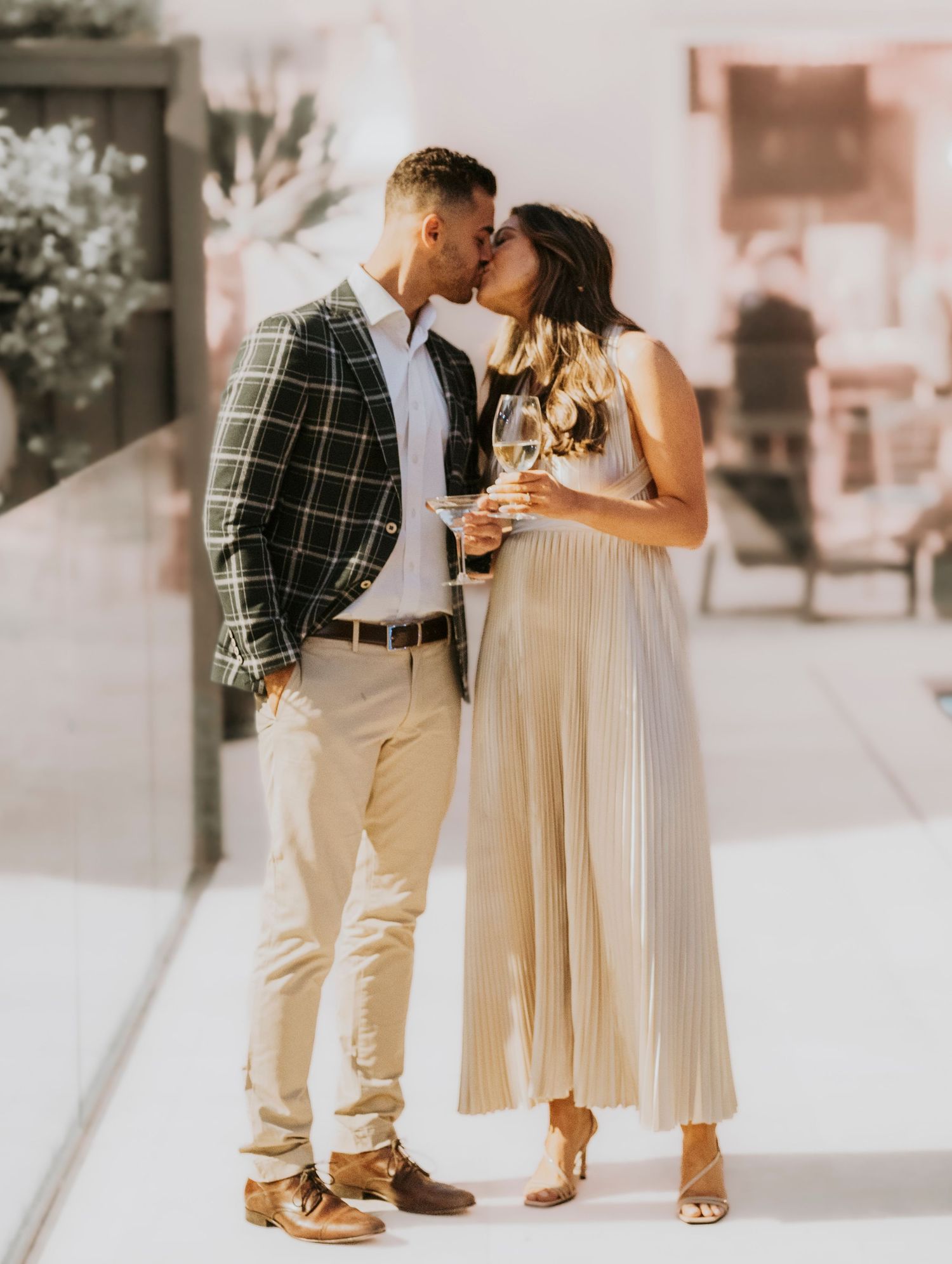 Couple in coordinated cream and black windowpane outfits share an intimate moment during a photoshoot.
