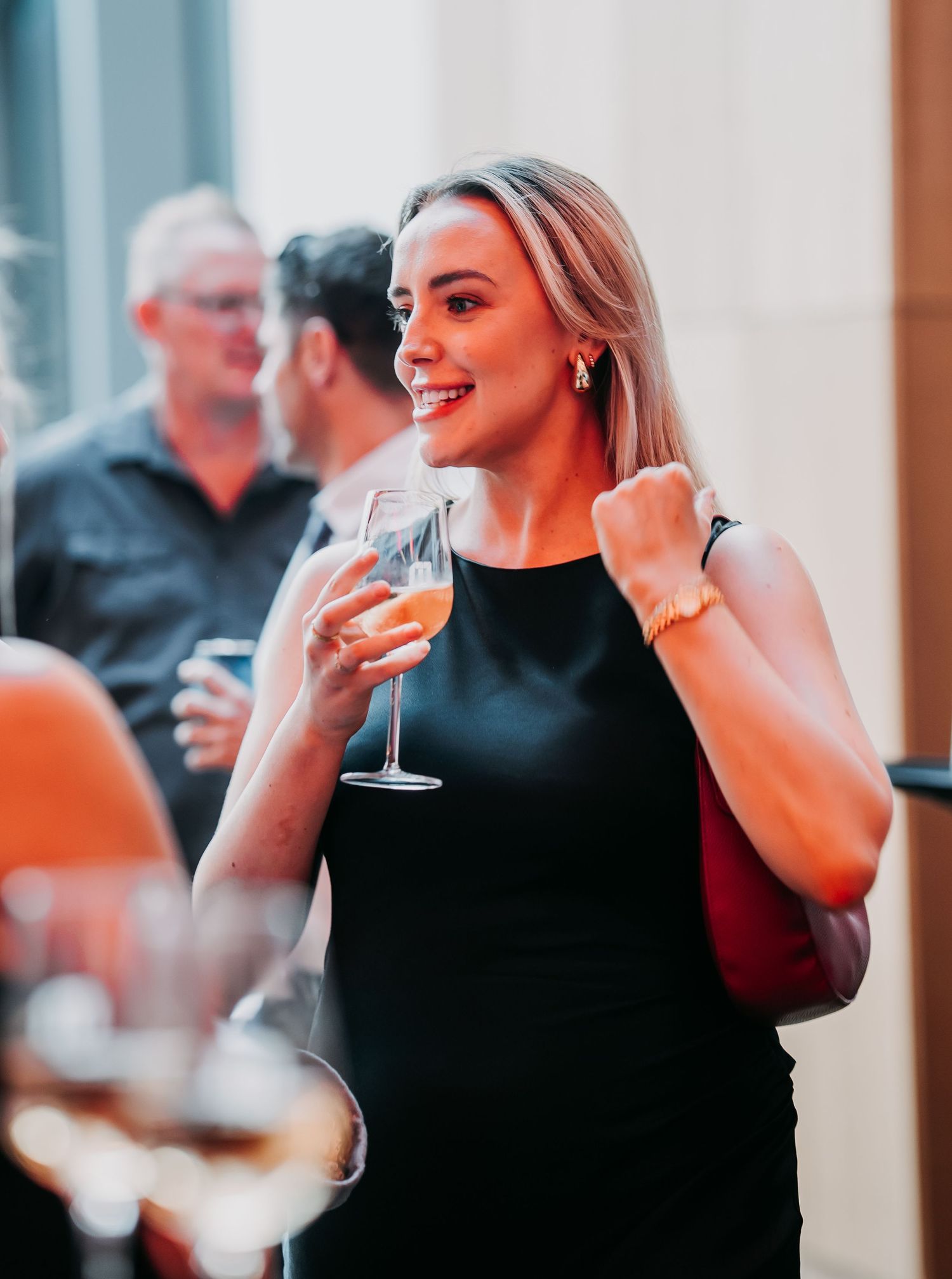 People enjoying drinks and conversation at a social gathering in a well-lit venue.