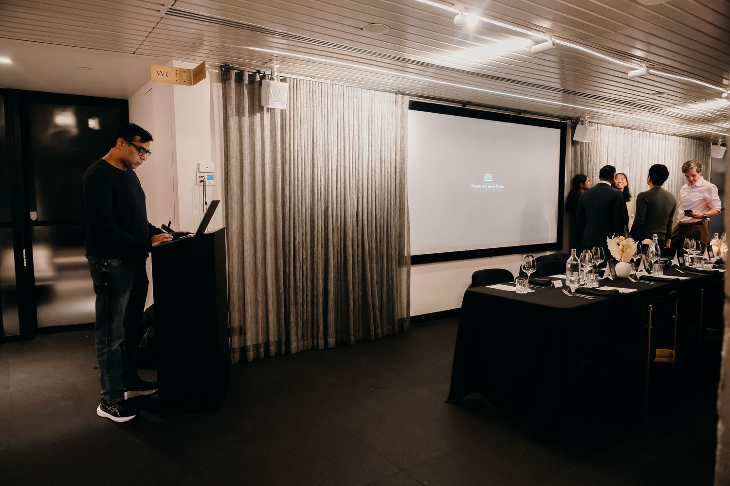 A series of dark interior event space photos showing dimly lit rooms with projector screens and audience seating.