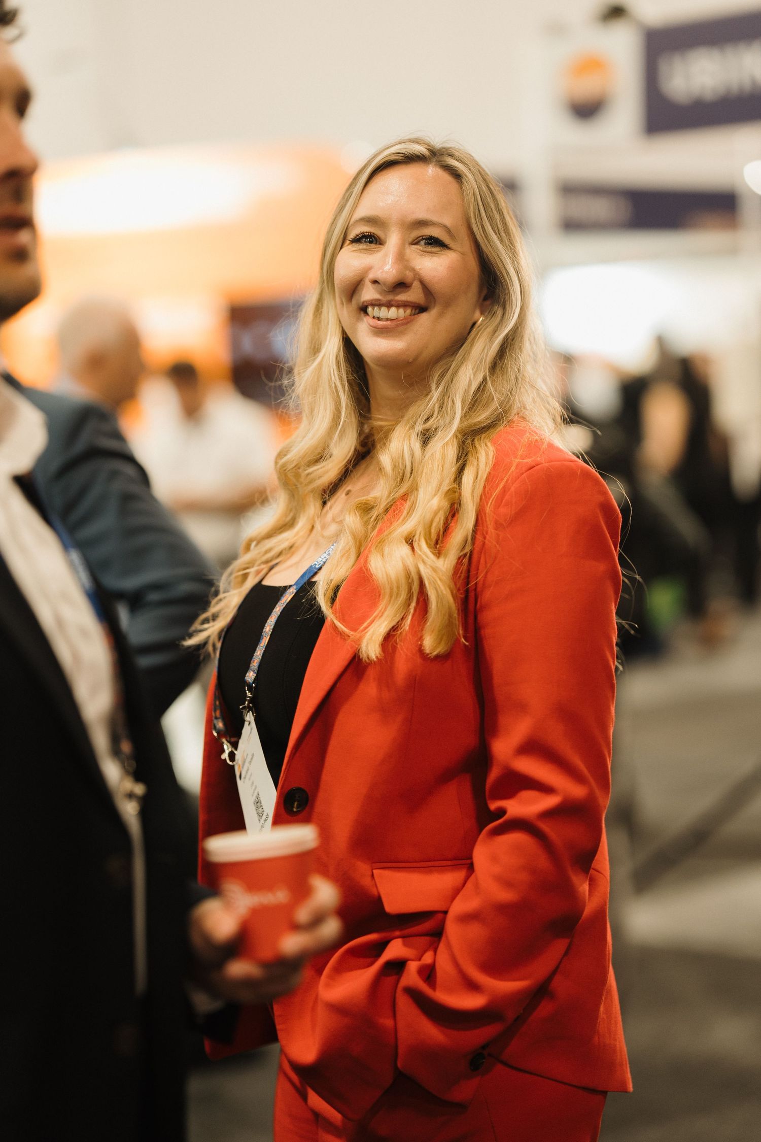 A person in a bright red blazer smiles while attending a professional event or conference.
