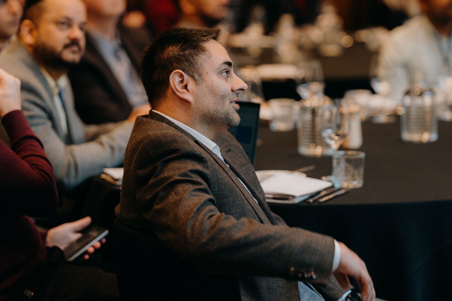 Professional speakers present to an engaged audience at a business conference in a modern meeting room setting.