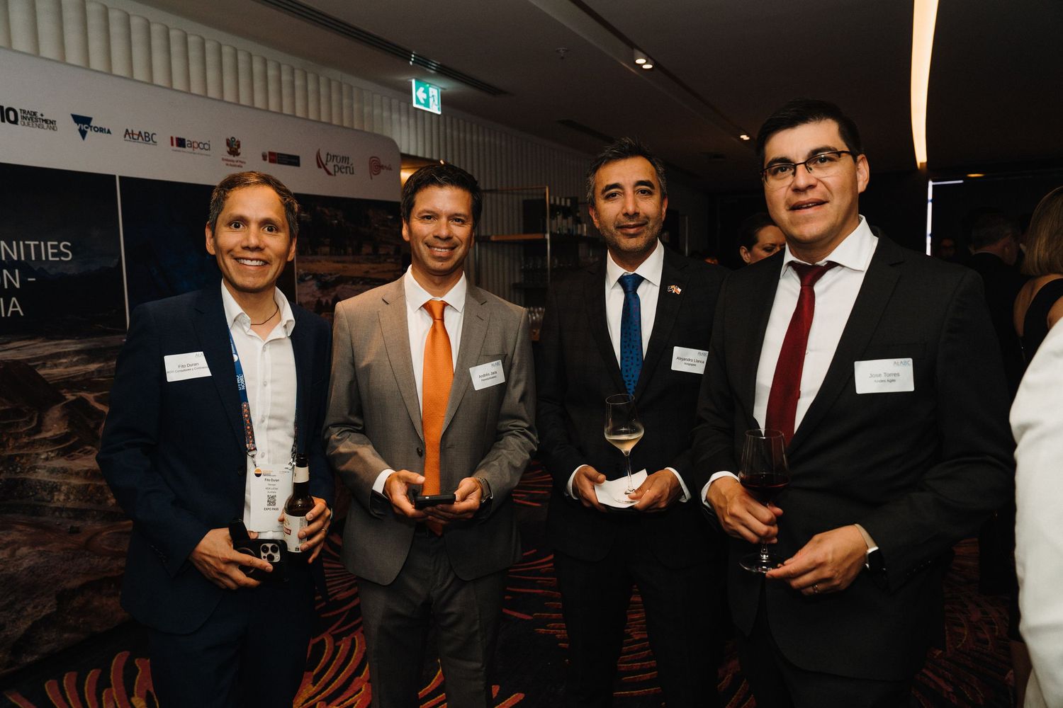 Business professionals networking and socializing at a formal corporate event with drinks and conversation.