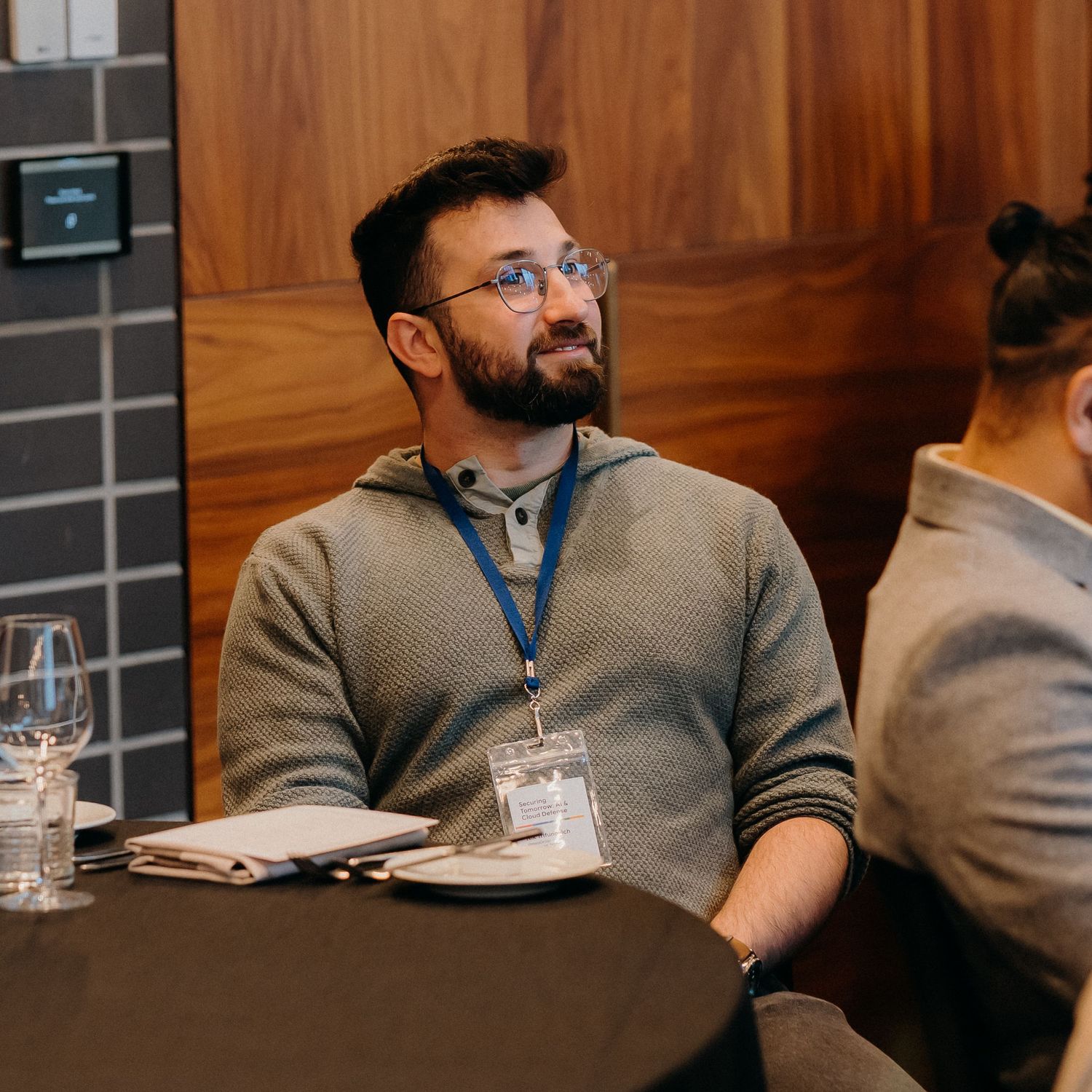 A person wearing a gray sweater sits at a conference table while working and taking notes during a meeting.