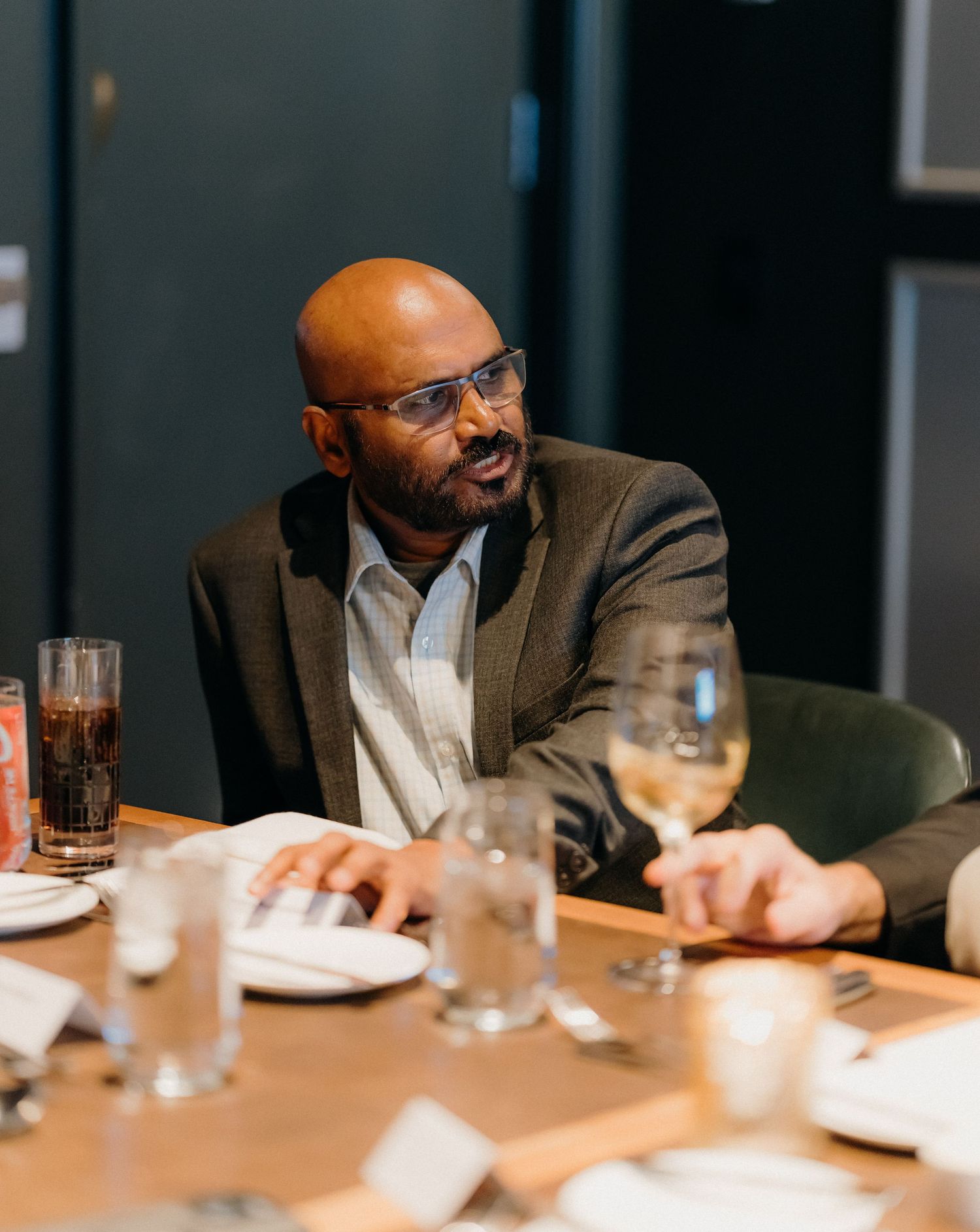 Business professionals share a lighthearted moment during a meeting at a conference table in a modern office setting.