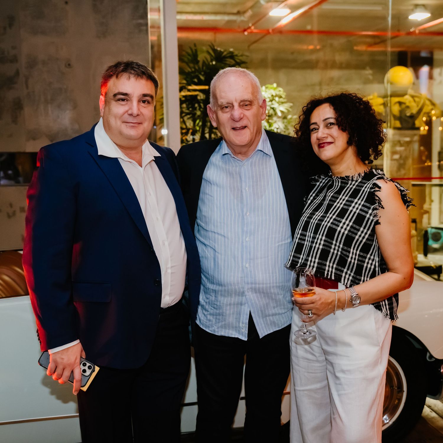 Group of people socializing and posing together at an indoor event space with bright lighting.