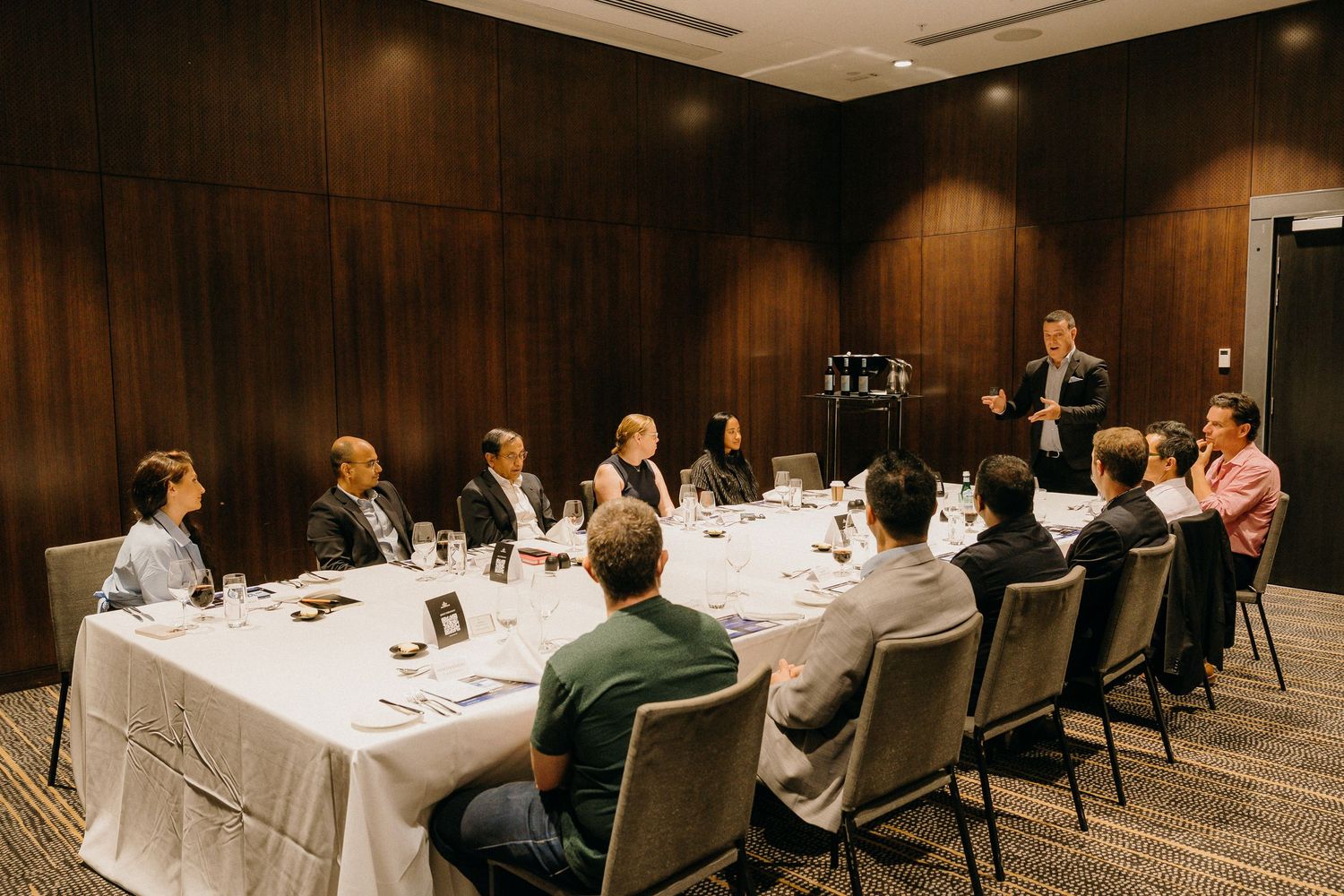 Business professionals seated at a formal conference table during a corporate meeting in a modern boardroom.