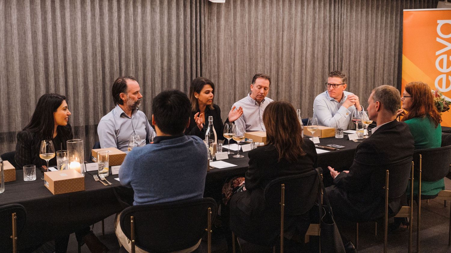 A long panoramic view of people seated at tables in a modern restaurant during a business meeting or gathering.