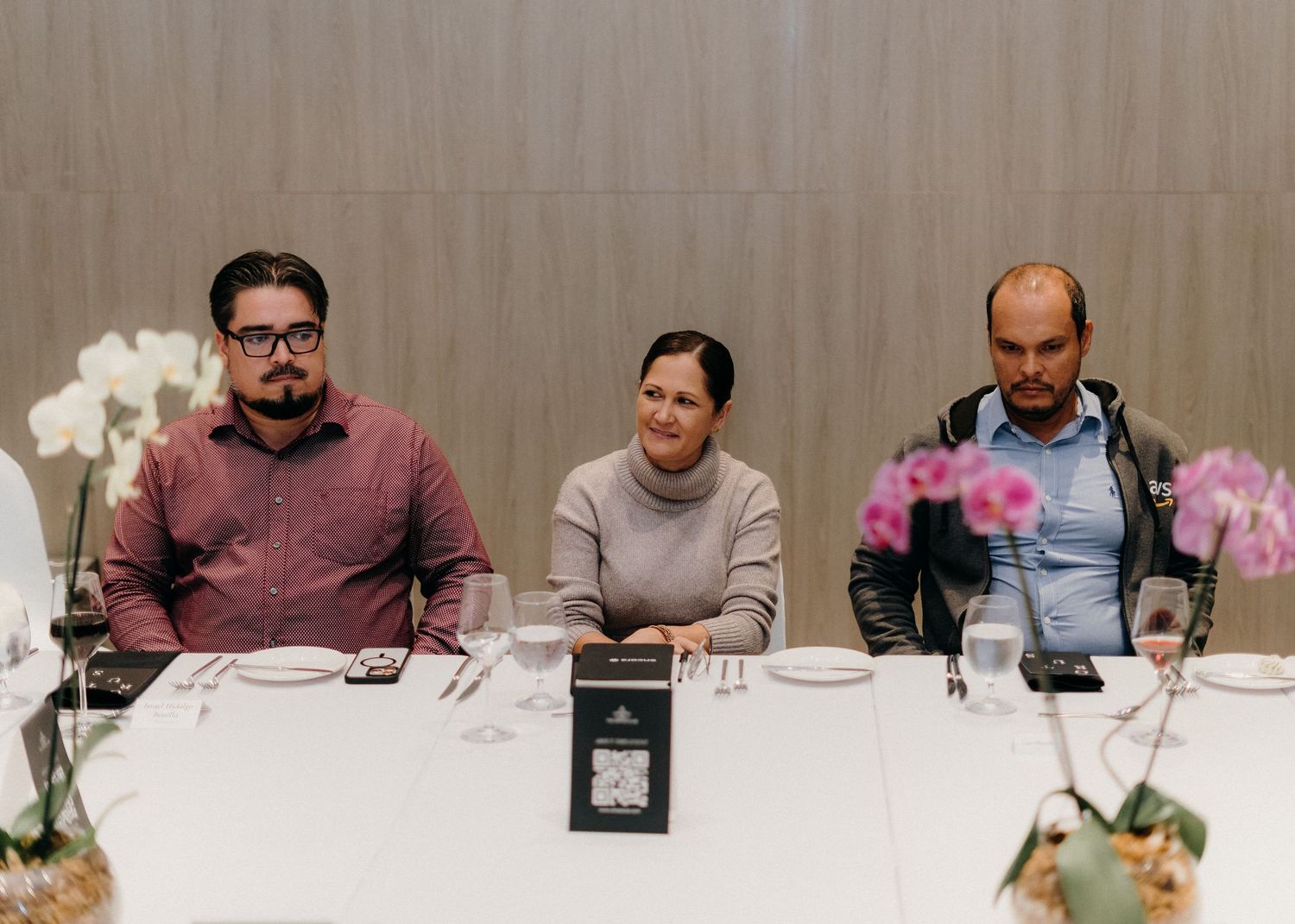 A group of people sitting at a long white table during a business meeting or conference.