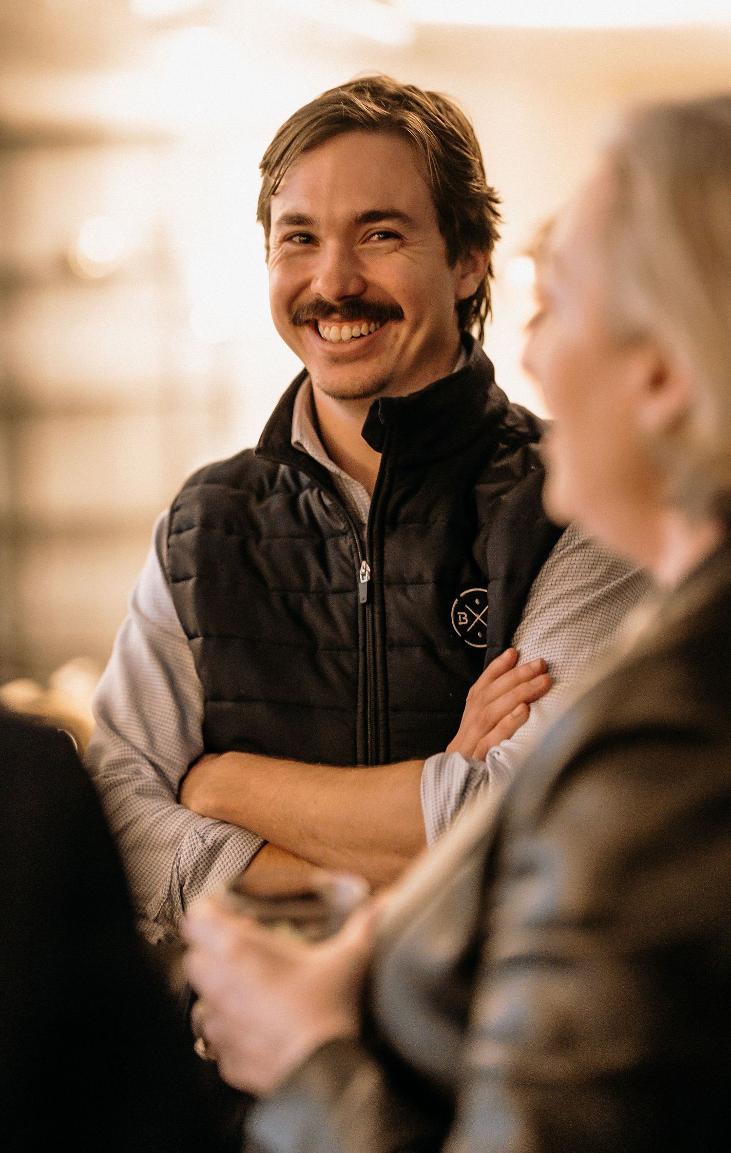 A sequence of candid shots showing someone in a black vest smiling and engaging in conversation.