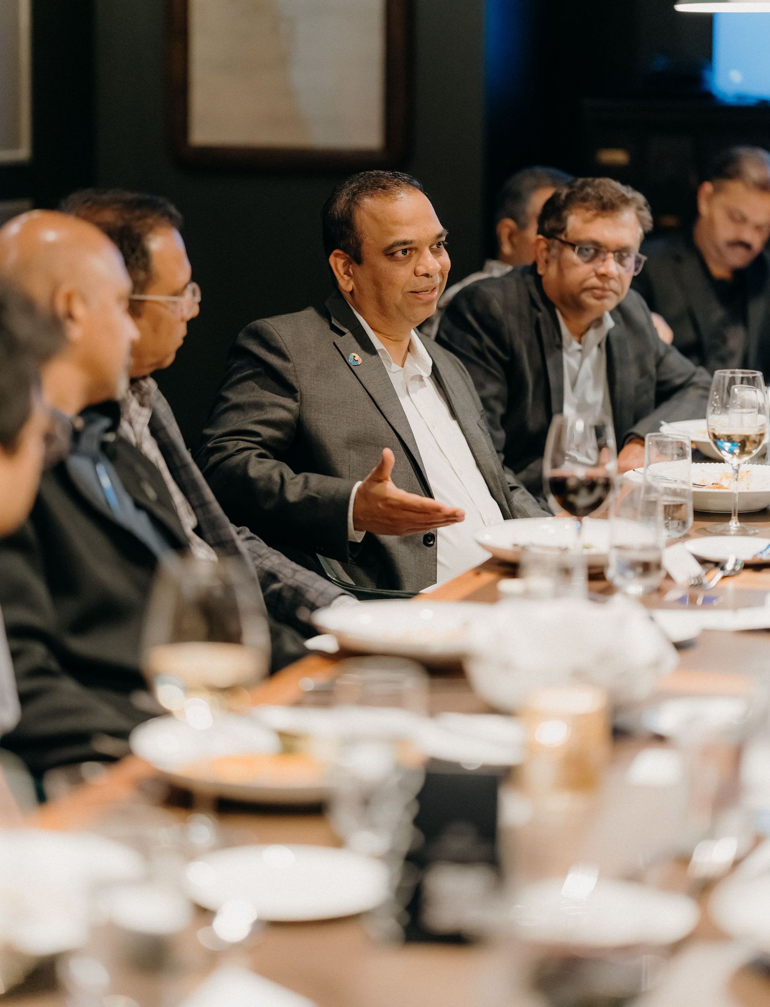 Business professionals seated at a long table during a corporate meeting or conference in a modern boardroom setting.