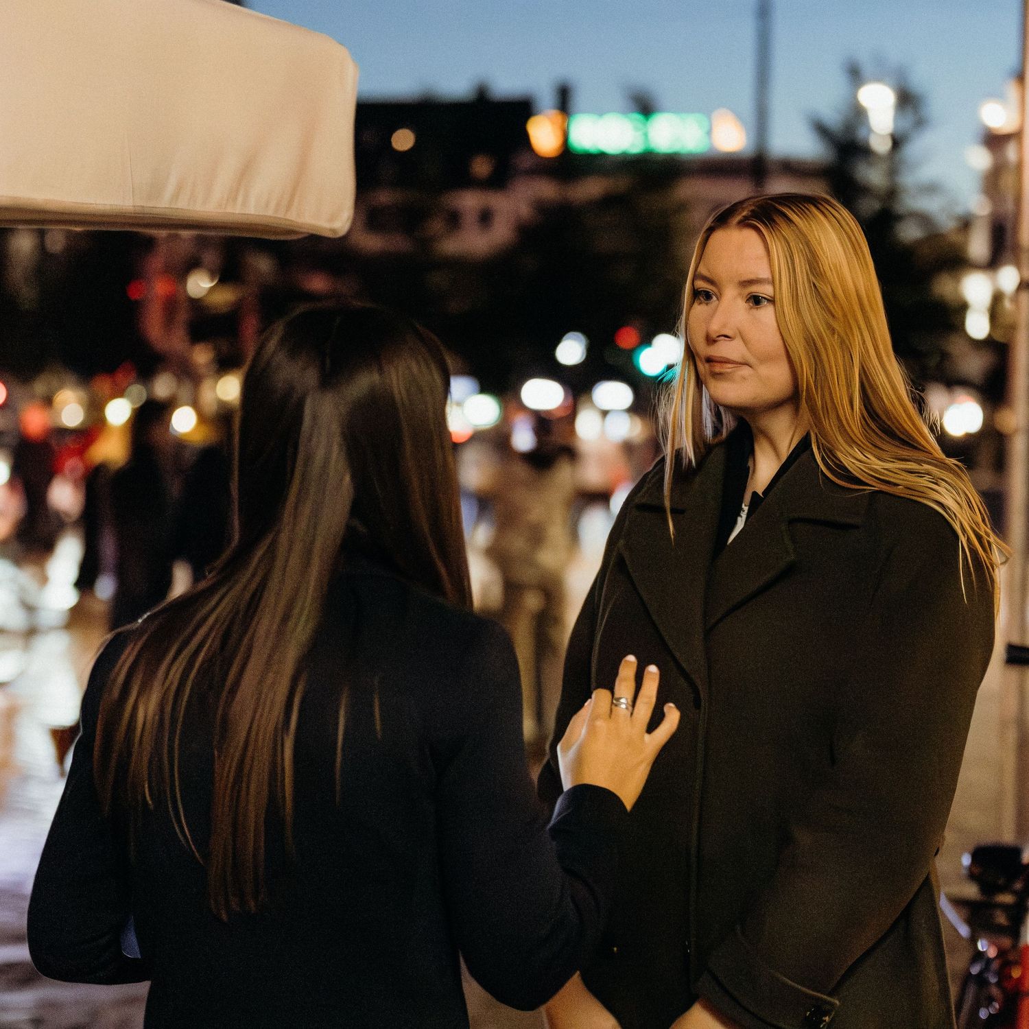 Group of people embracing and hugging each other at night with city lights in the background.