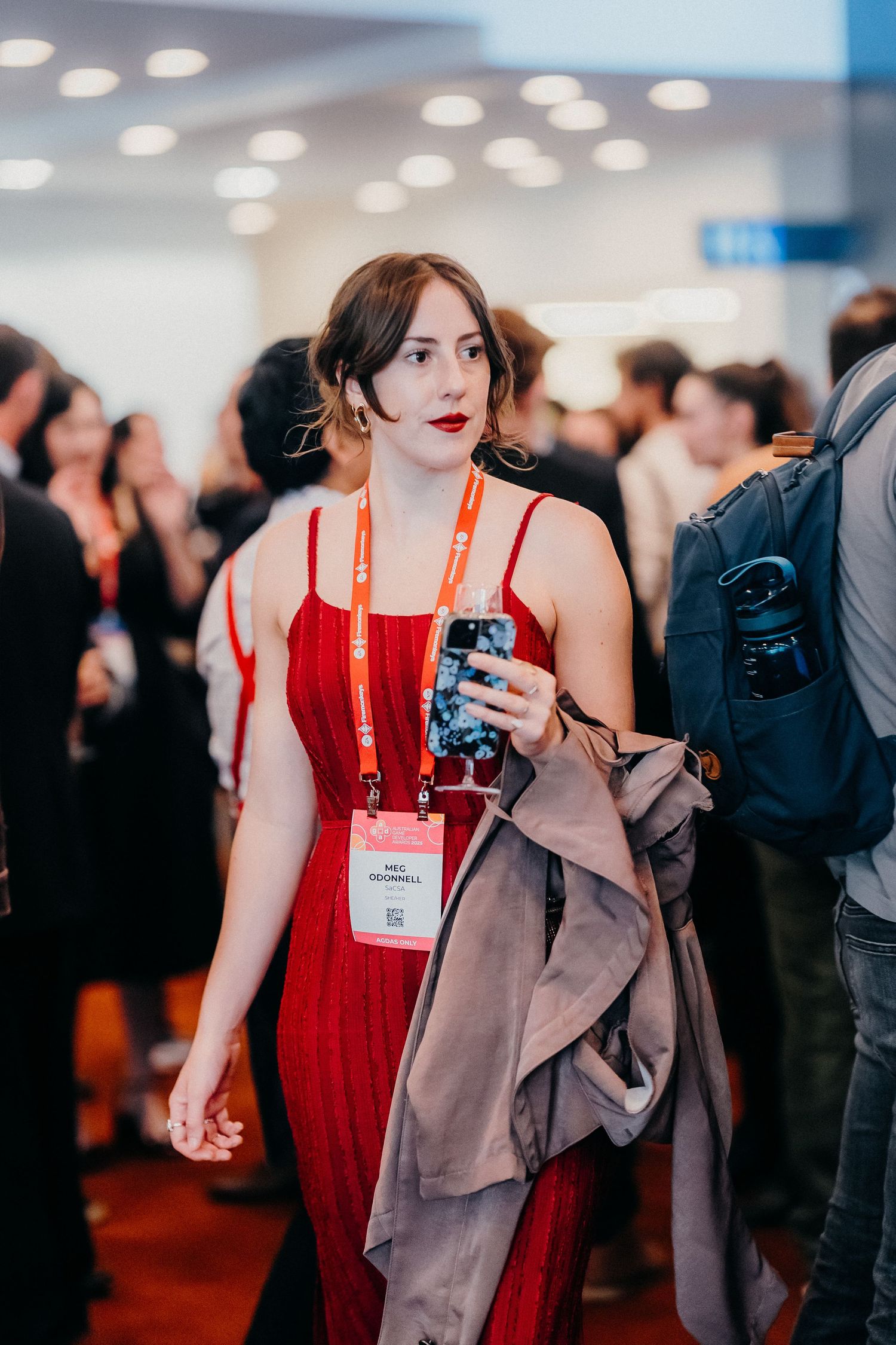 Conference attendees mingling in a bright indoor venue with red lanyards and name badges.