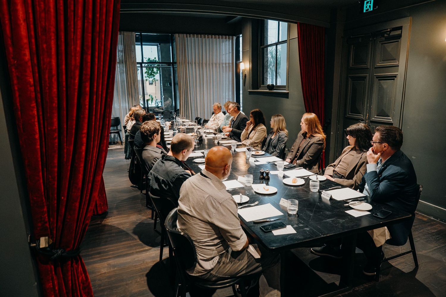 Business professionals seated around conference tables during a corporate meeting in a modern office space.