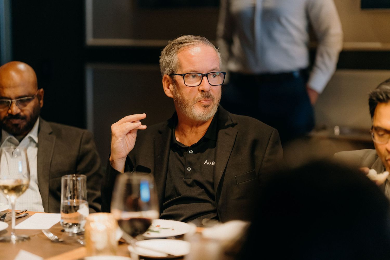 People seated at a restaurant table engaged in conversation during a business dinner meeting.