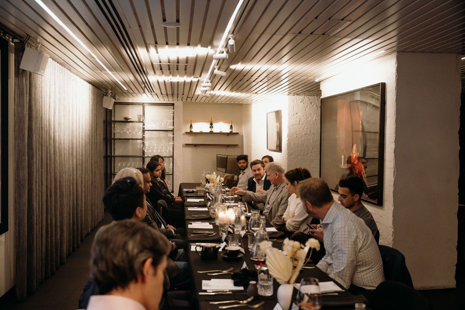 People gathered in a dimly lit office hallway with fluorescent lighting and metal ceiling panels.