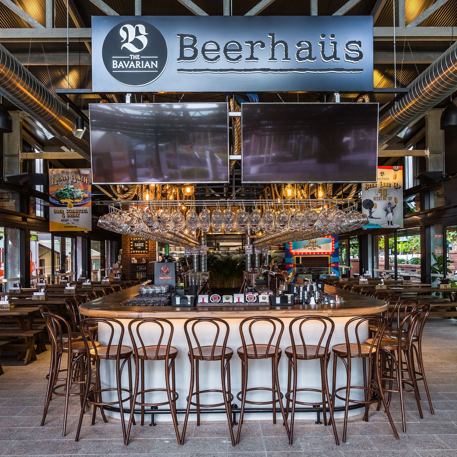 Modern beer hall interior with wooden chairs and exposed ceiling beams at empty Beerhaus restaurant and bar.