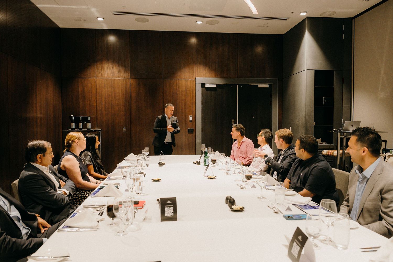 Business professionals gathered around a long conference table for a formal meeting in a modern boardroom.