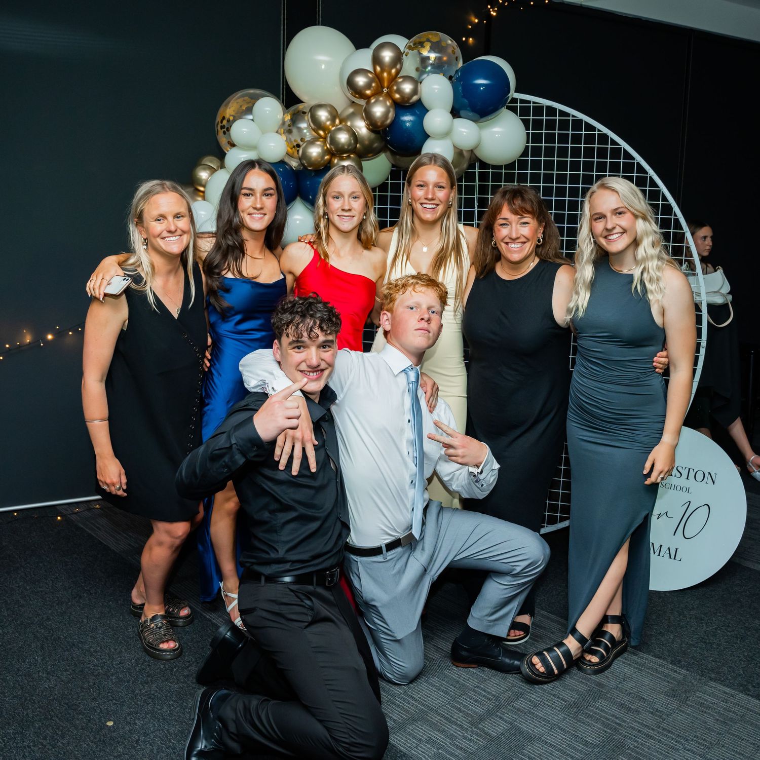 Party attendees pose together against a black backdrop in a series of celebratory group photos at an event.